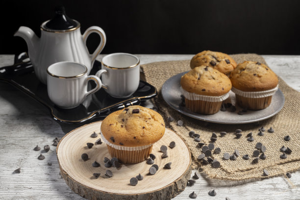 松饼或纸杯蛋糕，木桌背景是巧克力片。制作工业或自制糕点的概念。图片下载