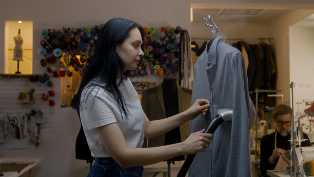 女裁缝用手持式蒸笼熨烫衬衫图片下载