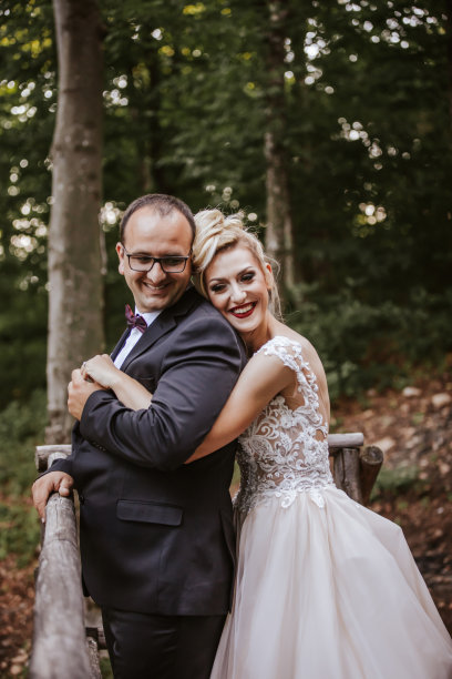 深情的年轻新娘和新郎站在大自然的木制露台上拥抱图片下载