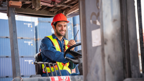 工程师或领班在集装箱堆场内工作并使用叉车，并穿戴个人防护装备。，航运、进出口行业内部的物流理念。图片下载