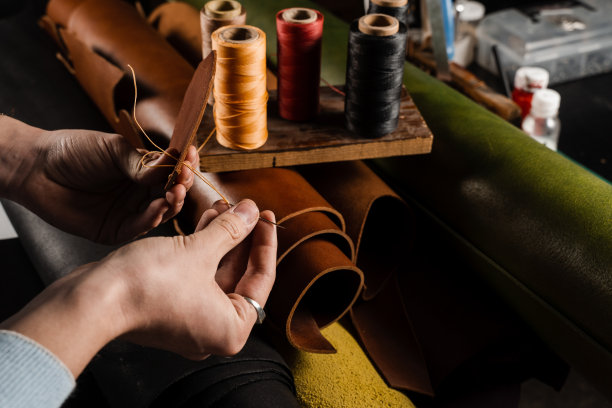 缝制真皮的过程。工匠用针和线缝制真皮，制作天然皮革制品。车间真皮生产设备。图片下载