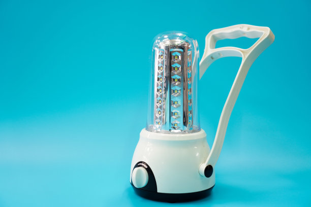 图片显示一个便携式LED灯，可以使用电池充电的蓝色背景，近距离。图片下载