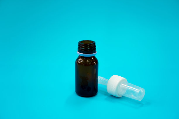 这张照片展示了一个耐光玻璃小瓶，蓝色背景上有一个供儿童使用的滴管。图片下载