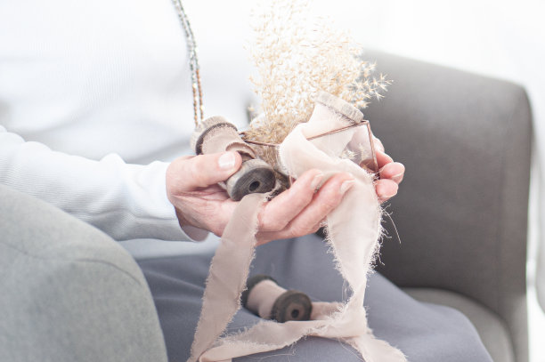 一位老妇人手里拿着鲜花和复古丝带。复古风格。光照片。图片下载