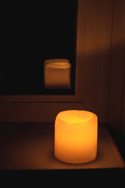 黄色的蜡烛在窗台上发出温暖的光。图片下载