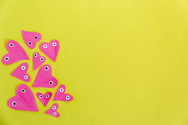 情人节或母亲节手工制品：黄色背景上手绘粉色纸质爱心，平铺，留有文字空间图片下载