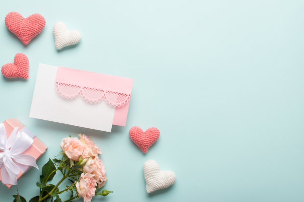 礼物上有一束鲜花和针织心形图案，还有一个淡蓝色背景的粉色花边信封。图片下载