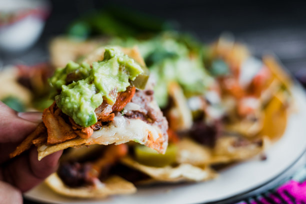 手拿墨西哥玉米片配美国奶酪和鳄梨，墨西哥拉丁美洲的传统食物图片下载