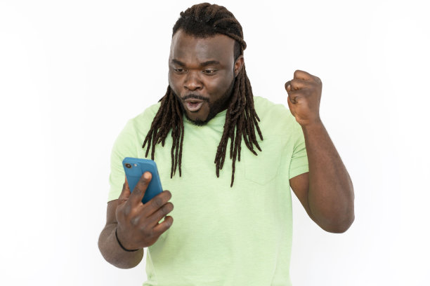 黑人男子一边看着手机屏幕一边庆祝胜利图片下载