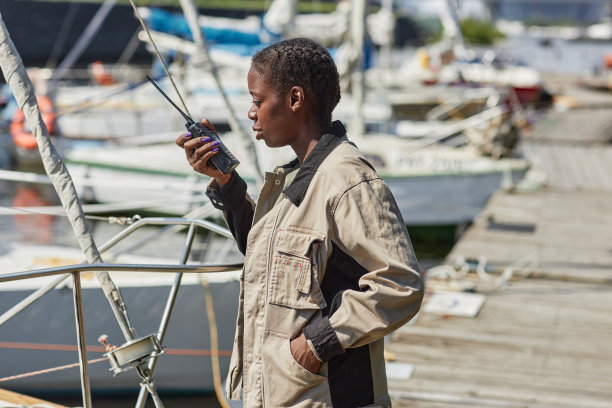年轻的黑人妇女拿着便携式收音机在游艇码头工作图片下载
