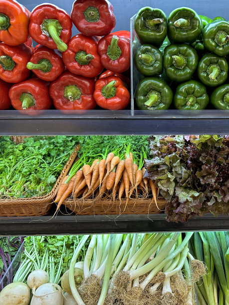 产品市场货架的全帧图像显示成堆的新鲜，水果和蔬菜，包括红色，绿色和黄色的灯笼椒(辣椒)，香菜，胡萝卜和生菜在柳条托盘，超市的杂货区，重点在前景图片下载