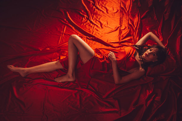 躺在红色床单上的年轻女子图片下载