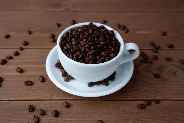 烤好的咖啡豆放在桌上的咖啡杯里图片下载