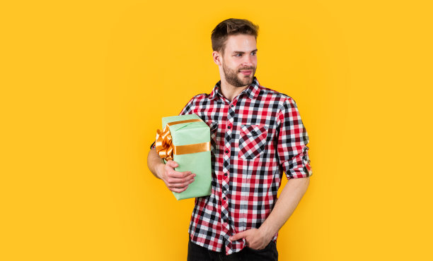 年轻英俊的男子在衬衫拿着礼物盒，周年纪念图片下载