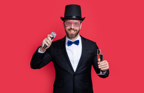 魔术师用麦克风欢呼。男子魔术师穿燕尾服在工作室。图片下载