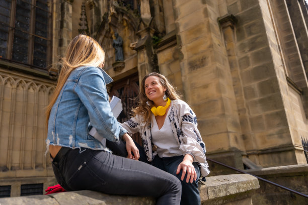 特写镜头是两个年轻的白人女性坐在教堂旁边，享受一天图片下载