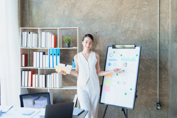 年轻的亚洲妇女手持笔记本电脑的肖像，介绍战略，投资计划和营销。图片下载