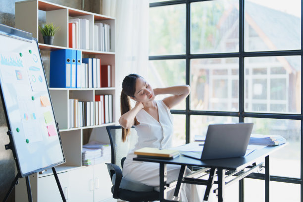 一位年轻的亚洲女性因长时间坐着工作而患有急性头痛和枕骨疼痛。图片下载