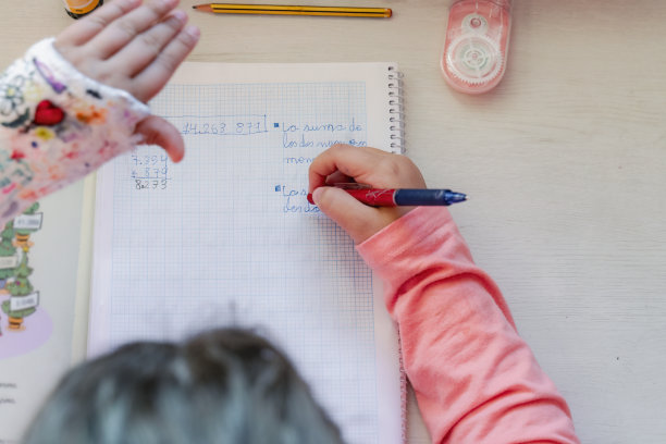 俯视图，一个面目全非的女孩在笔记本上做数学作业。有计算障碍的女孩，很难做数学计算。图片下载