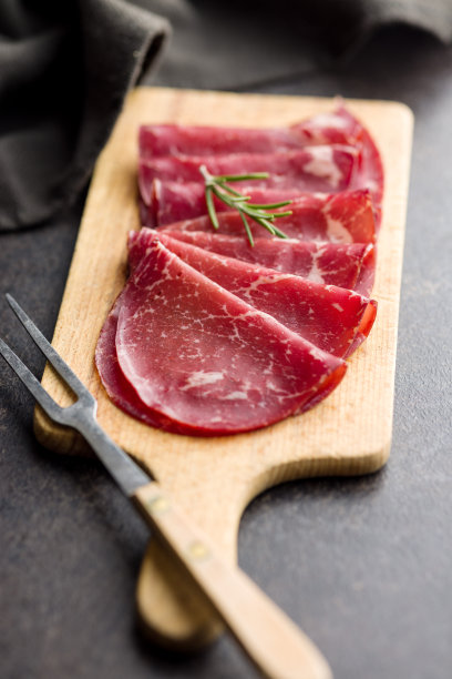 烟熏bresaola。意大利开胃菜。牛肉干放在砧板上。图片下载