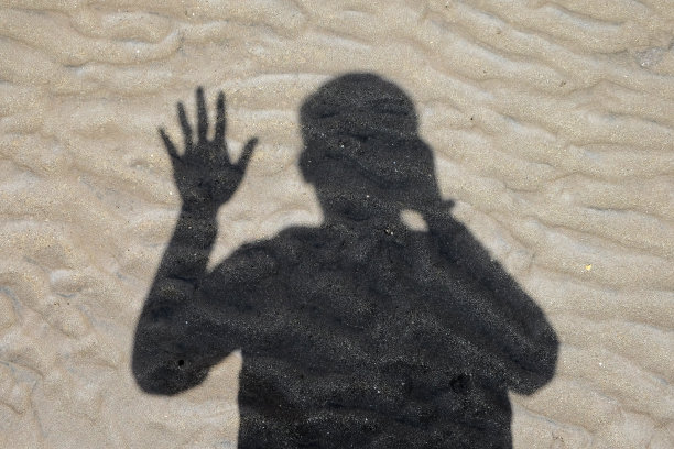 男人的影子在波浪沙滩上挥手在白天，夏天旅行的背景图片下载