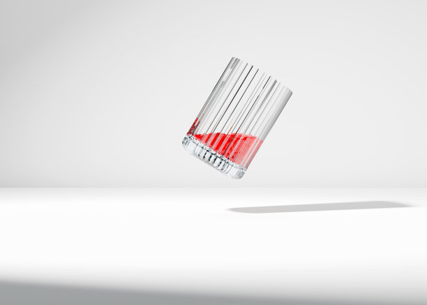 倾斜的罗纹杯，盛满鲜红的果汁。在白色工作室背景中悬浮在半空中。图片下载