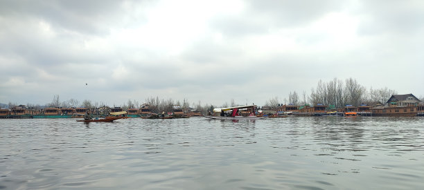 湖面上船只的全景照片，树木在多云天空下的倒影图片下载