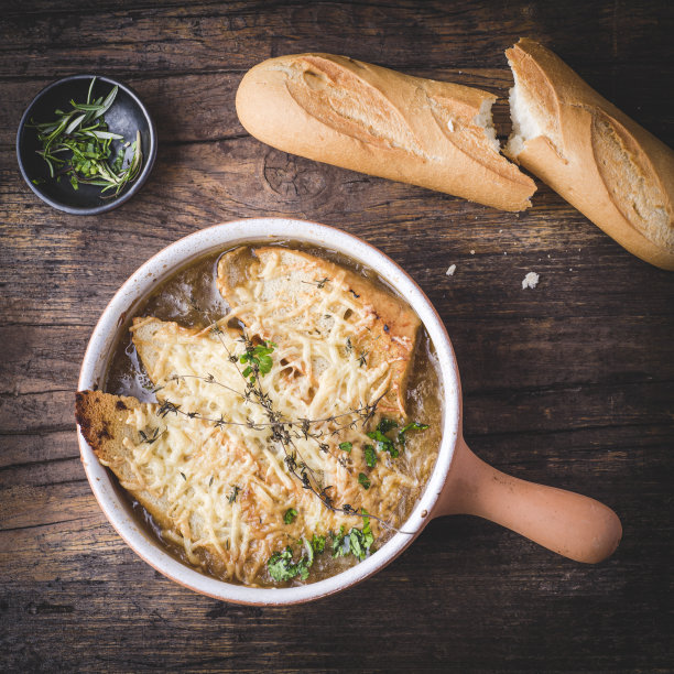 经典的法式洋葱汤，用奶酪面包丁烘烤，在质朴的木质背景上撒上百里香，配上法棍面包。法国，法国的味道，健康的食谱，方形作物图片下载