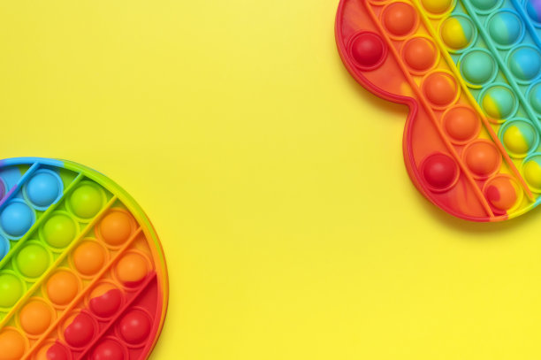 流行硅胶多色抗压力玩具pop在心形和圆形的黄色背景平铺顶视图。时髦的现代感官儿童玩具，烦躁推挤吧图片下载