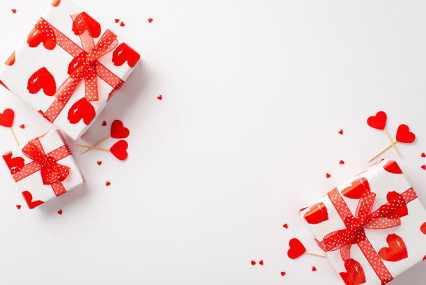 情人节的概念。俯视图照片的礼物盒与红丝带蝴蝶结心形棒和洒在孤立的白色背景与空白图片下载