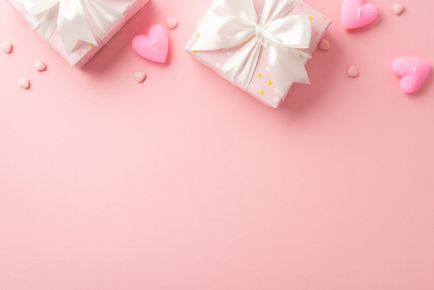情人节的概念。顶部视图大礼物盒与缎带蝴蝶结心形蜡烛和洒在孤立的浅粉色背景与空白的照片图片下载