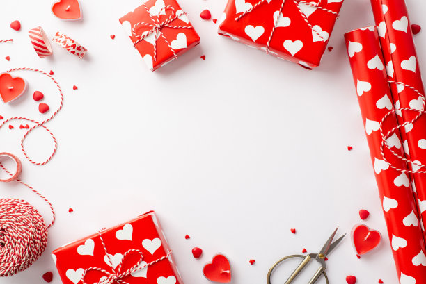 情人节的概念。礼盒的顶部视图照片心形蜡烛线轴的麻绳剪刀胶带包装纸卷洒在孤立的白色背景与中间的copyspace图片下载