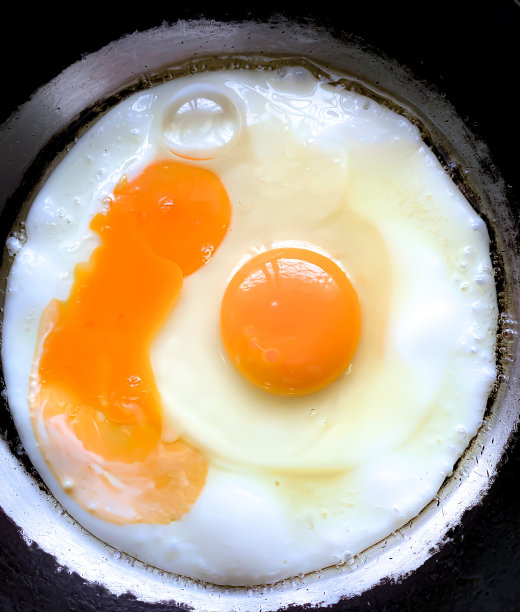 在热锅里煎蛋看起来很开胃。这是一份简单的早餐。蛋黄含有胆固醇，蛋清含有增肌蛋白。图片下载