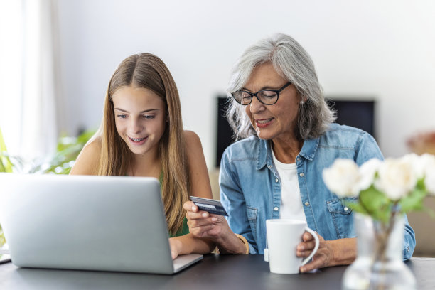 快乐的奶奶和孙女在家里用笔记本电脑用信用卡网购。图片下载
