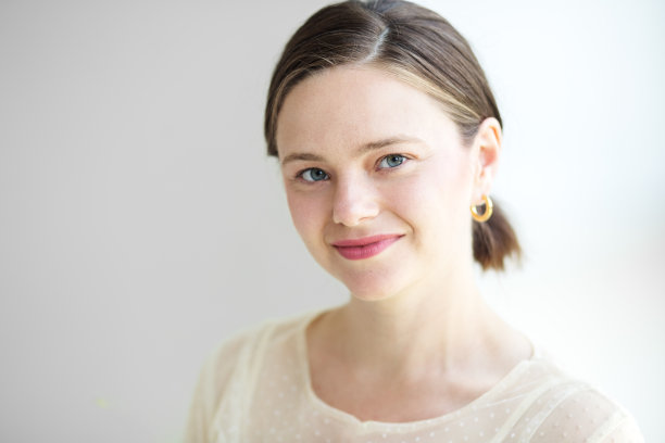 精致美丽的女人靠在白墙上。图片下载