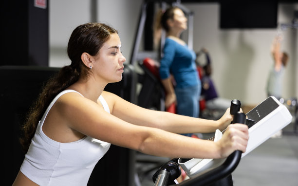 白人妇女在健身房使用运动自行车图片下载