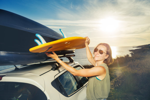 一名妇女从车顶行李架上取下冲浪板图片下载