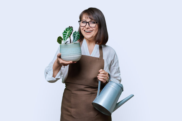 女人在围裙浇水罐和盆栽，白色背景图片下载