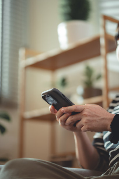 在家里客厅沙发上放松时，女性使用智能手机的手特写镜头。图片下载