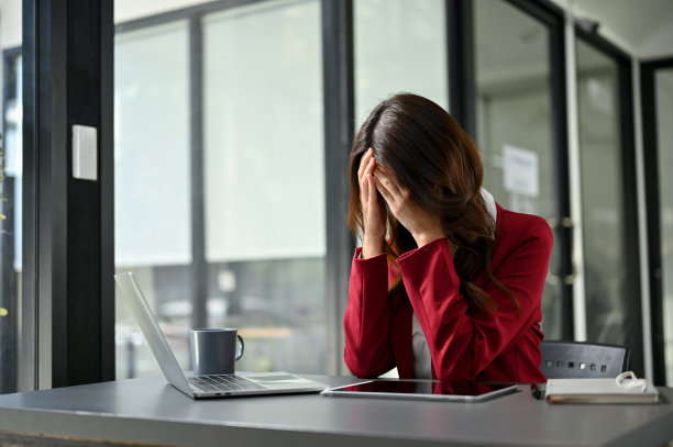 压力和沮丧的亚洲女商人坐在她的办公桌前，担心她的项目。图片下载