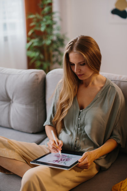 快乐的年轻设计师在绘图板上用触控笔画画。有创造力的年轻自由职业者在她的家庭办公室工作。图片下载