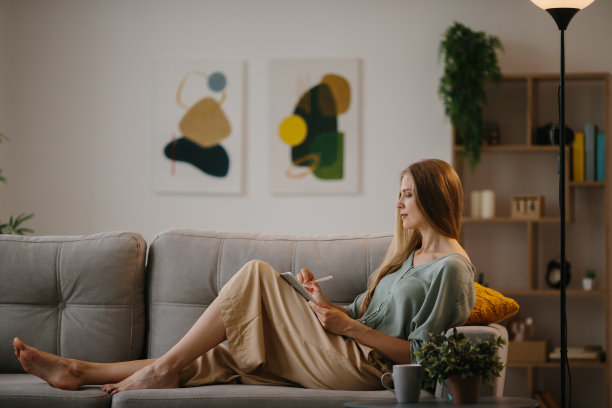 漂亮的金发年轻女子插画家在平板电脑上画画。图片下载