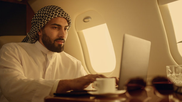 正面ceo在出差时输入笔记本电脑特写。微笑的阿拉伯人享受着图片下载