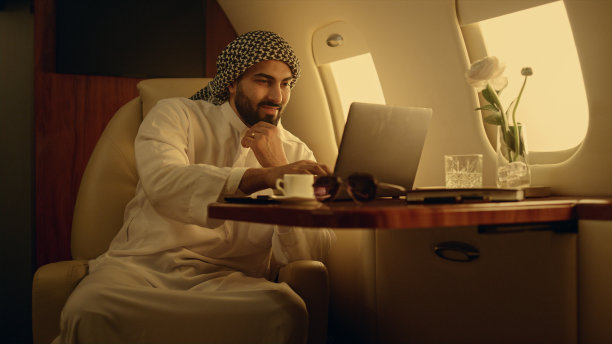 微笑的商人在飞机上打字。快乐男子在线聊天图片下载