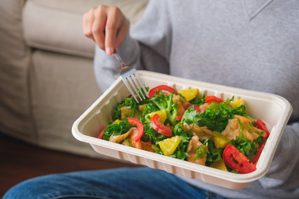 一个女人在家里吃盒装的沙拉外卖的特写图片图片下载
