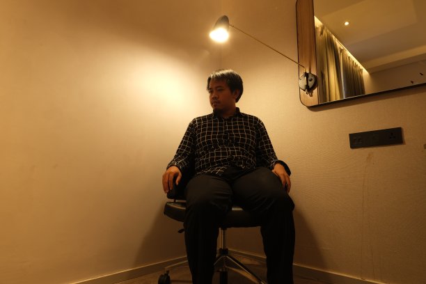 神秘的剪影男子坐在灯光下或聚光灯下图片下载