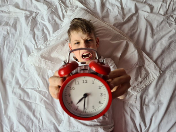 愤怒的男孩，孩子，青少年对闹钟生气，不想起床图片下载
