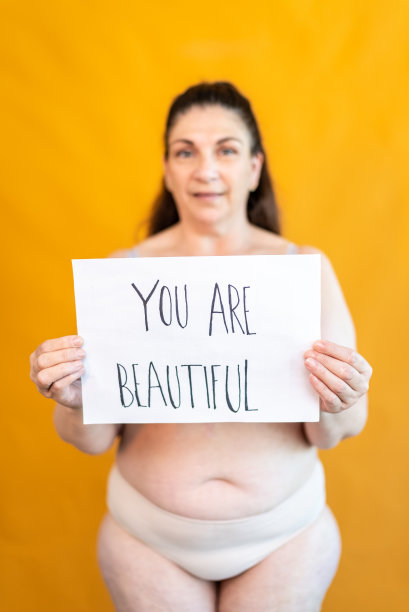 一个成熟的女人拿着一张写着“你很漂亮”的纸的肖像图片下载