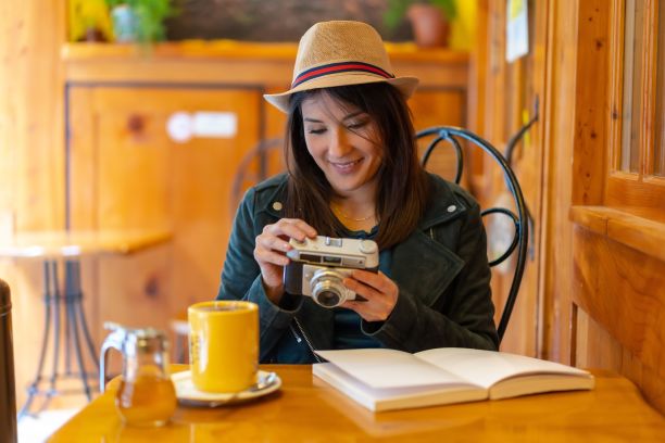 拿着相机的西班牙游客女孩在自助餐厅露台喝茶图片下载