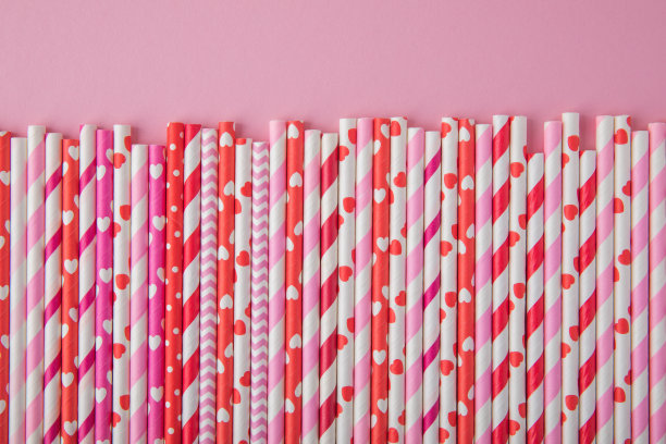 为情人节喝吸管。粉色背景上的红色、粉色和白色派对纸吸管图片下载